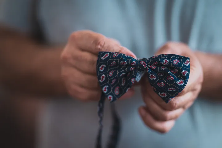 Le mani di Gaetano tengono un papillon a fantasia.