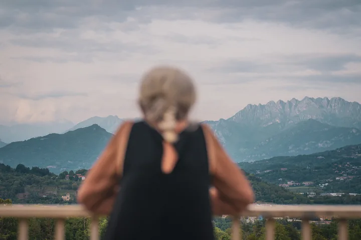 Una donna di spalle osserva il panorama delle montagne.