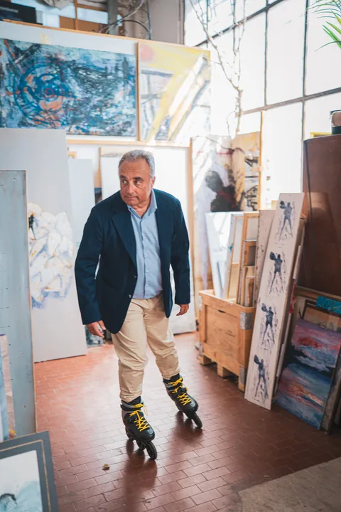 Un uomo sui pattini in linea tra le tele dell’atelier.