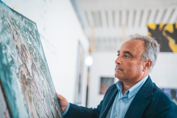 Un uomo osserva da vicino una tela nell’atelier.