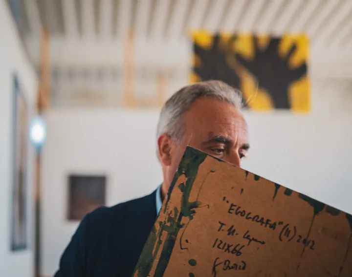 Un uomo tiene una tela di cui si vede il retro scritto.