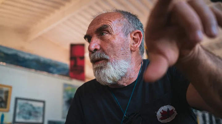 Gaetano tende una mano verso l’obiettivo nel suo atelier.