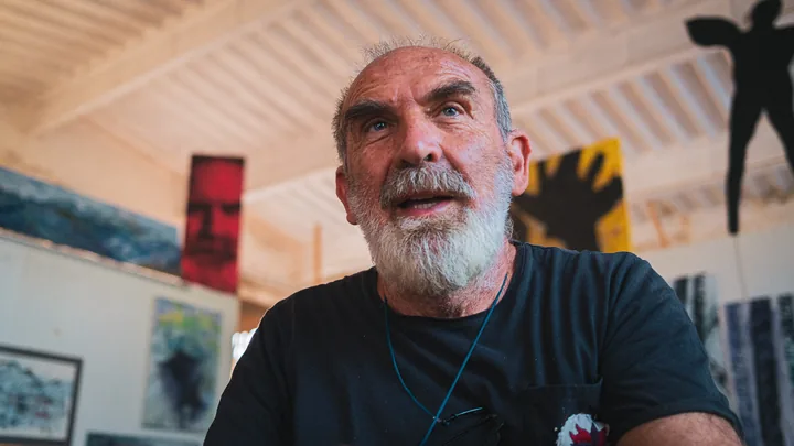 Gaetano parla davanti alle tele del suo atelier.