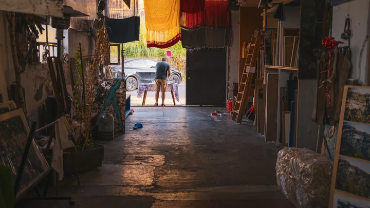 L’atelier in penombra si apre su una porta luminosa.