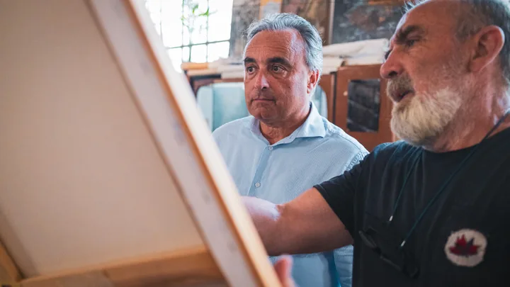 Due uomini osservano una tela nell’atelier.