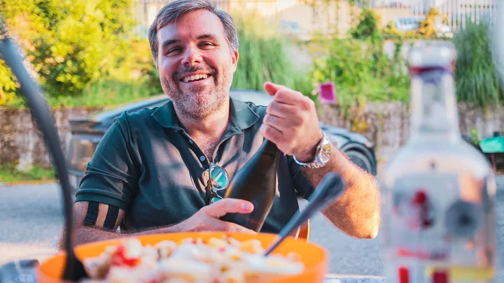 Un commensale sorride a tavola, in giardino.