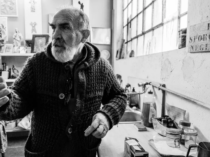 Gaetano in cardigan scuro davanti a una finestra, in bianco e nero.